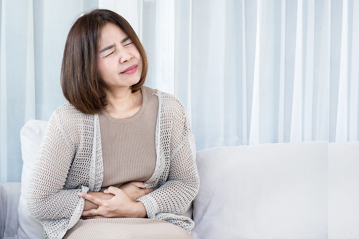 Woman holding her lower abdomen while experiencing pelvic discomfort and pain.