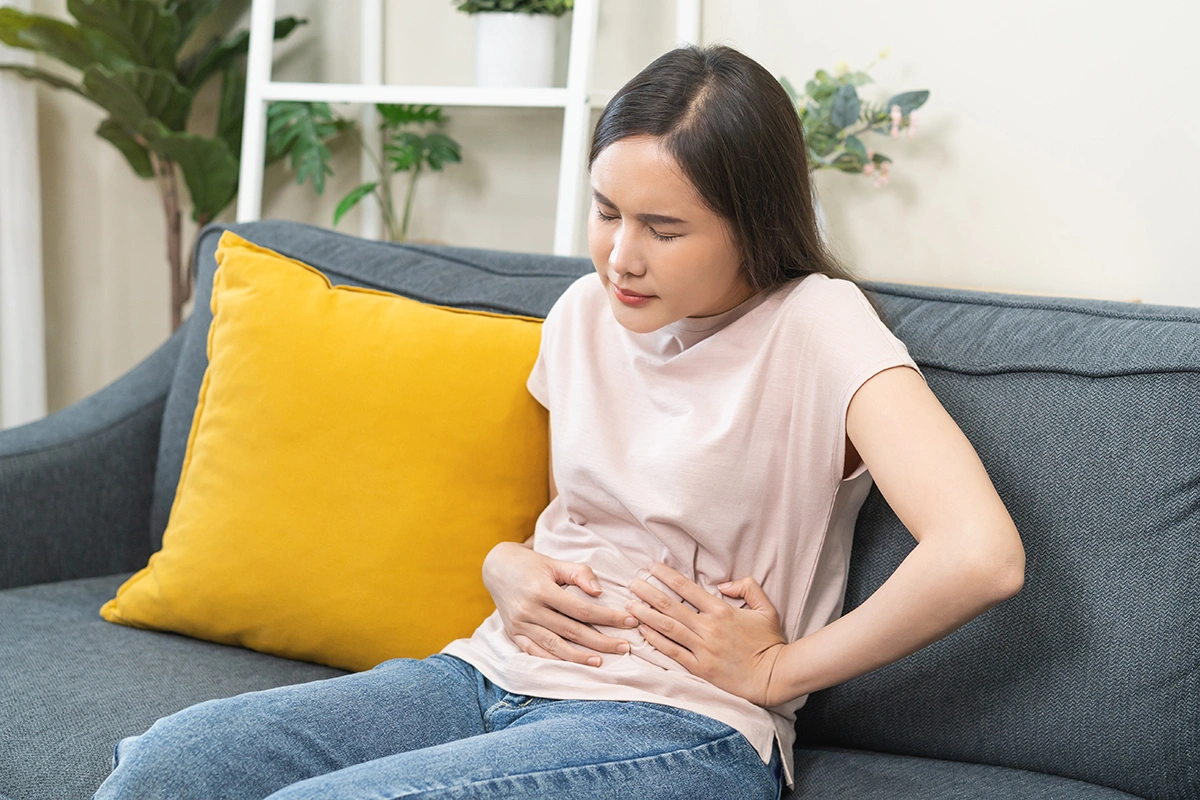 Woman holding her lower abdomen, indicating discomfort or abdominal pain.