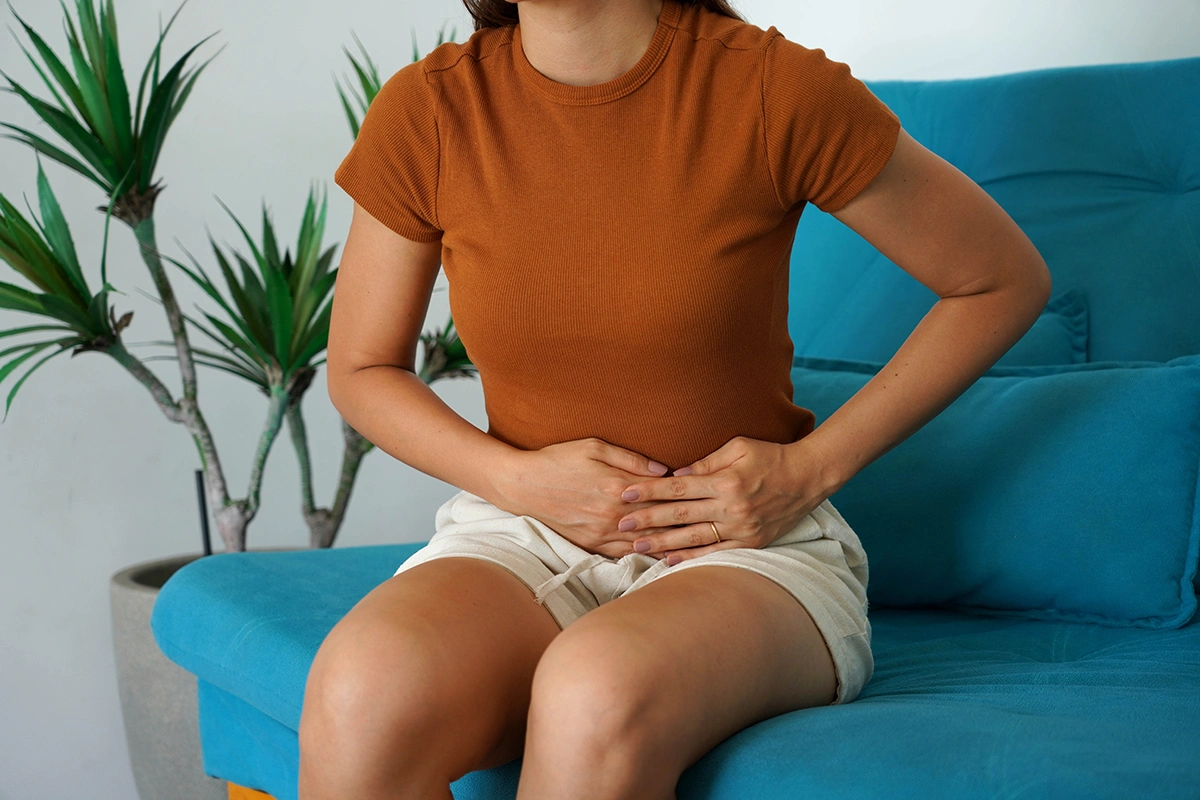 Woman holding her lower abdomen while experiencing pelvic discomfort and pain.